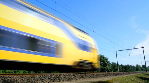 Yellow and blue old passenger train passing by at high speed.