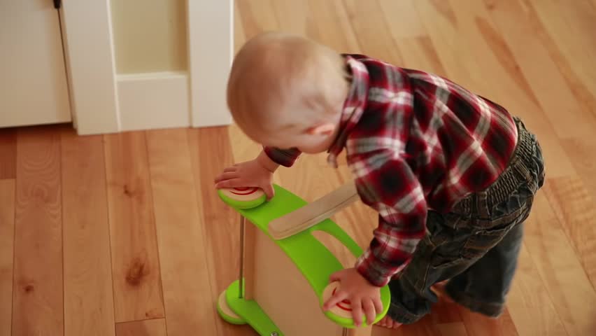 A boy toddler playing with his push toy in the kitchen