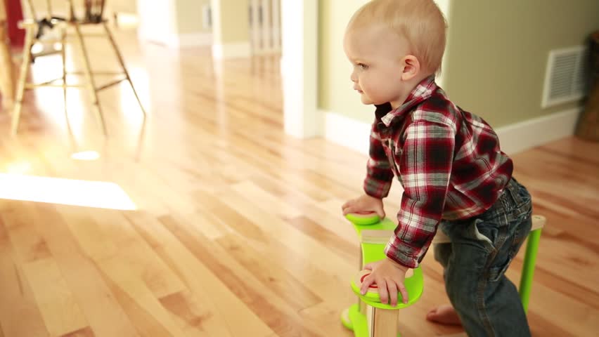 A boy toddler playing with his push toy in the kitchen