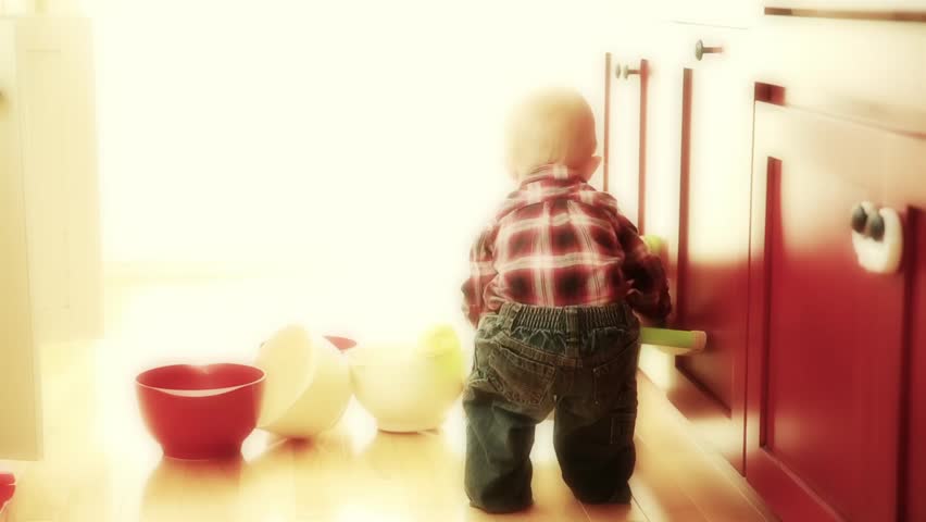 A little boy crying while playing with a push toy in his kitchen