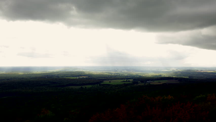 Luminous clouds flowing over a broad expanse of countryside dotted with farms and forest. Early fall colors are beginning to show. View from Rib Mountain, Wisconsin, midwest USA.