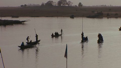 Boats are rowed in silhouette on the Niger River in mali, Africa.