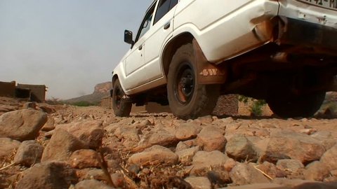 MALI-CIRCA 2012-A UN type jeep drives down a stone covered road in rural Mali.