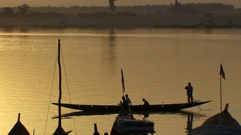 Boats are rowed on the Niger River in beautiful golden light in Mali, Africa.