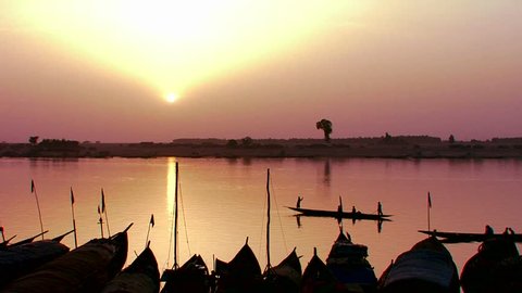 Fishermen row at sunset on the Niger River in beautiful golden light in Mali, Africa.