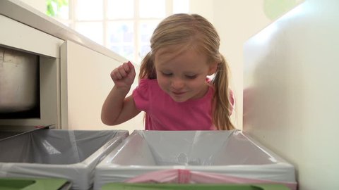 Girl drops plastic bottle into kitchen recycling bin in slow motion 库存视频
