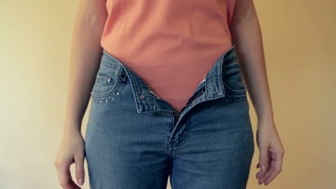Young woman observing her too large pants after a big weight loss. High definition video.
