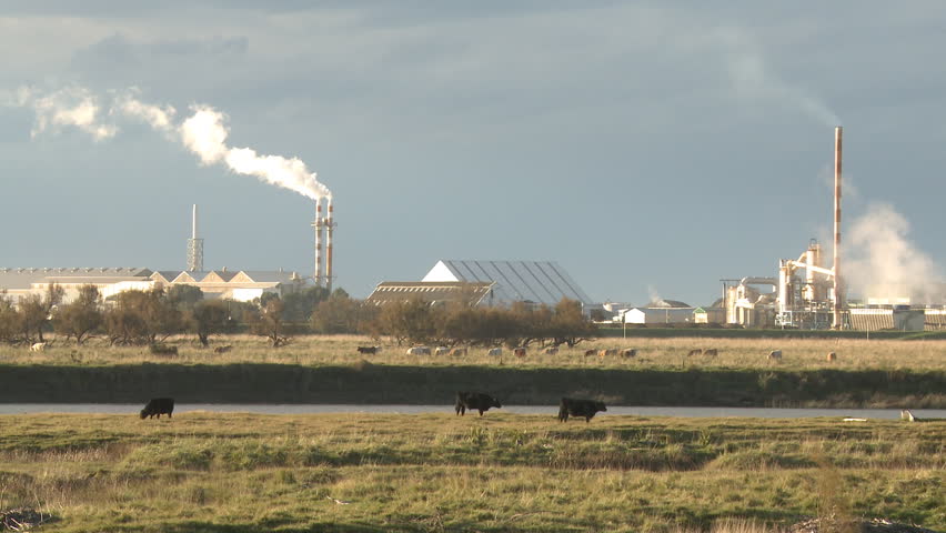 Industrial plant seen in the distant across farmland