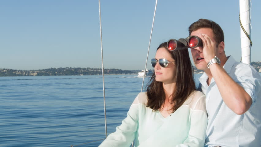 Young couple have fun while on a sail boat in Seattle, Washington.  Man holds
