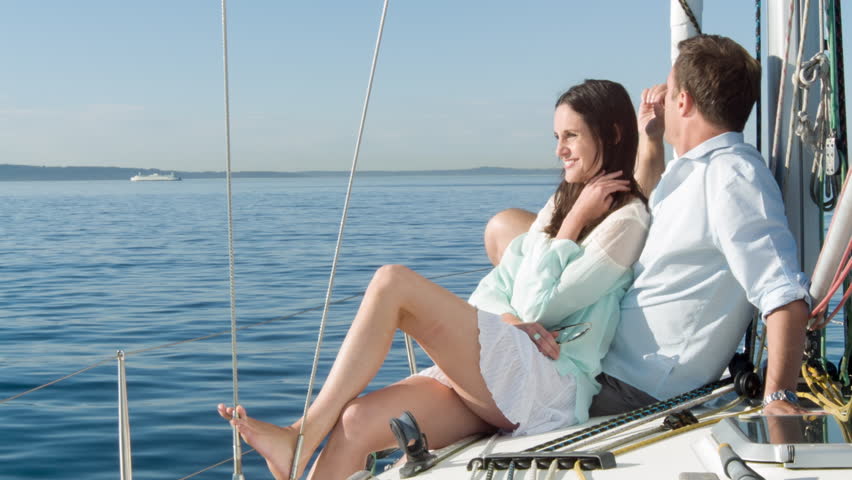 Young couple enjoy each others' company, sitting on the deck of a boat, sailing