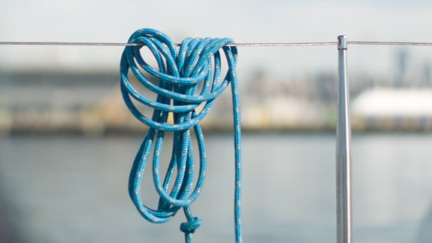 Close up of a rope hanging on a sail boat as it travels on the water.