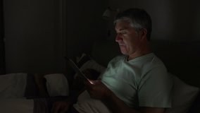 Middle aged man turns off digital tablet and goes to sleep beside wife - Powered by Shutterstock - Get 15% off with code: PIKWIZARD15