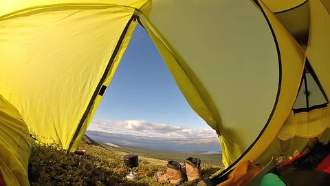 View of the mountain valley with lake through the window in the camping tent 