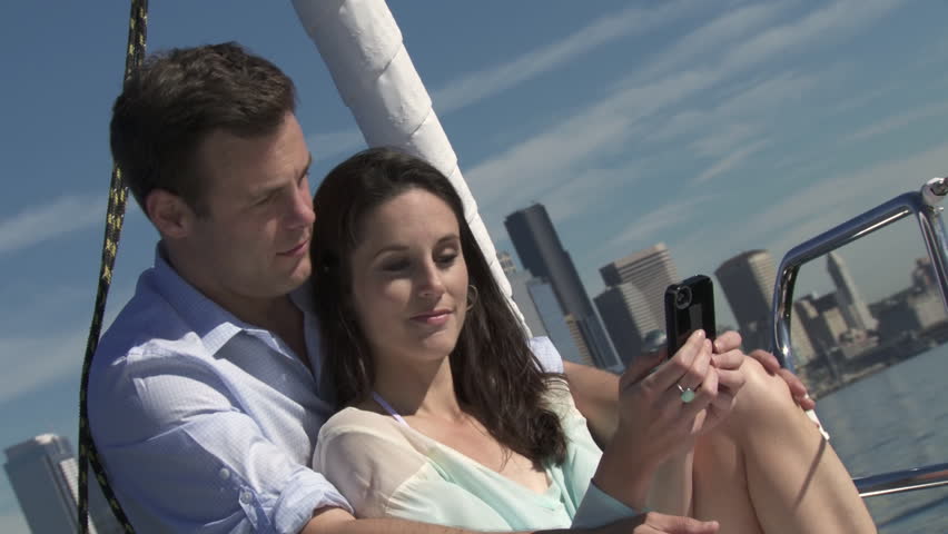 Young couple take pictures of themselves and the city skyline as they sit at the