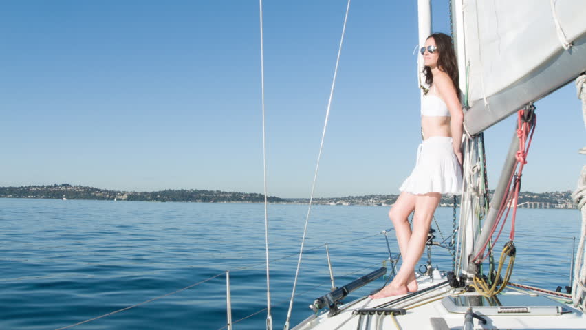 Young woman in a white bathing costume and short skirt, stands on the deck of a
