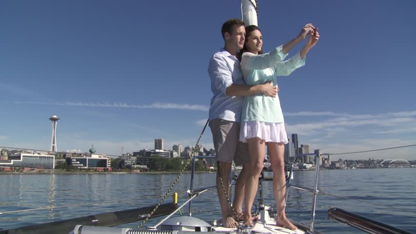 Young couple take pictures of themselves and the city skyline as they stand at