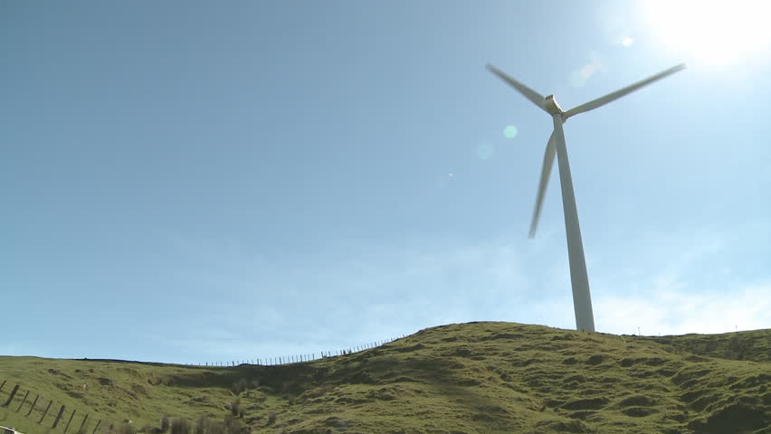 A large wind turbine casts shadows on the hillside