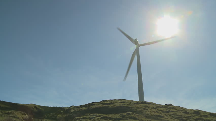 A large wind turbine on a hill generating power from the wind