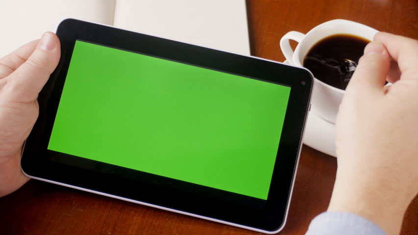 Man watching green screen on tablet PC in cafe