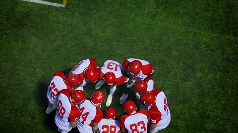 A birds eye view of a football team discussing the next play while in a huddle