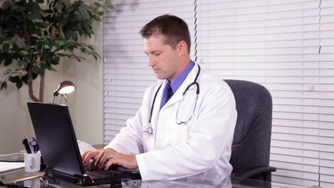 Two doctors consulting one another about test results they see on a chart and on a laptop.