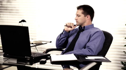 A young, attractive, businessman deep in thought about something that causes him stress. High contrast tint for drama