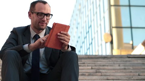 Young businessman with tablet computer sitting in the city
 Stock Video