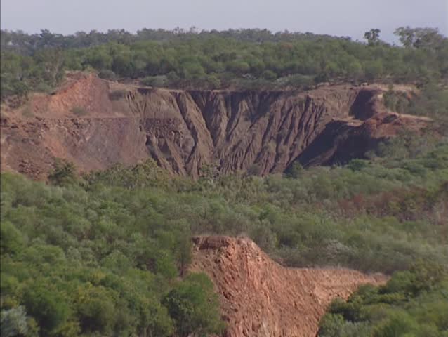 Pine Creek, Australia:  Close up gold mine on slope + zoom out closed open-cut gold mine pit, filled with water.