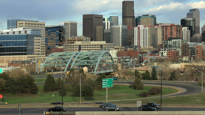 Slow pan and zoom out of Denver Skyline, with fast-moving interstate traffic in