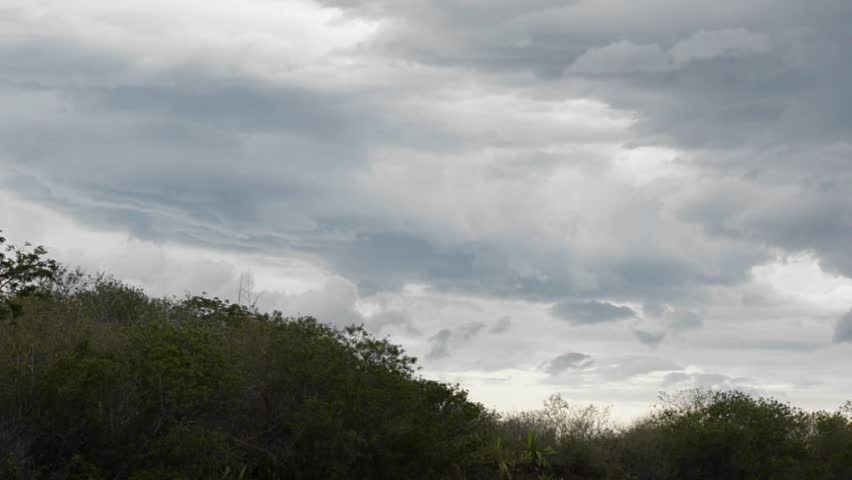 Storm clouds appear over a hilly landscape.