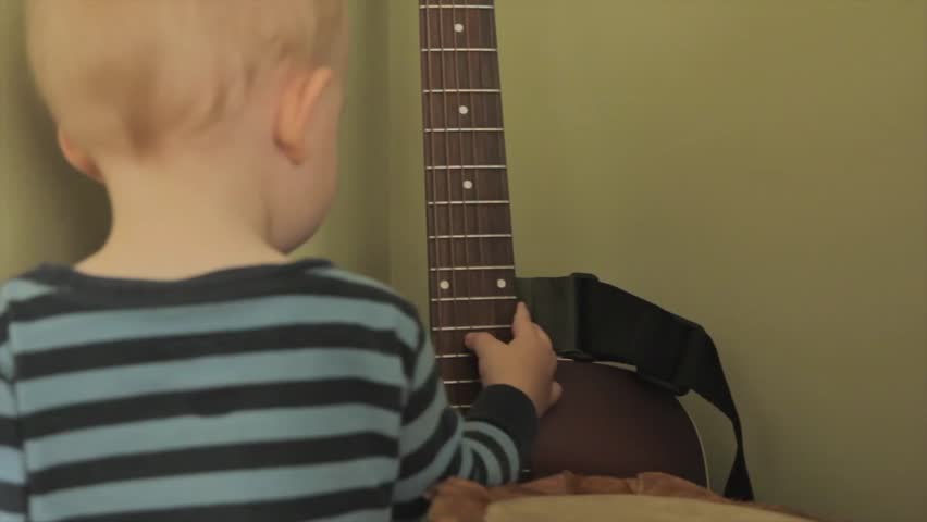 A little boy playing with a guitar and a drum