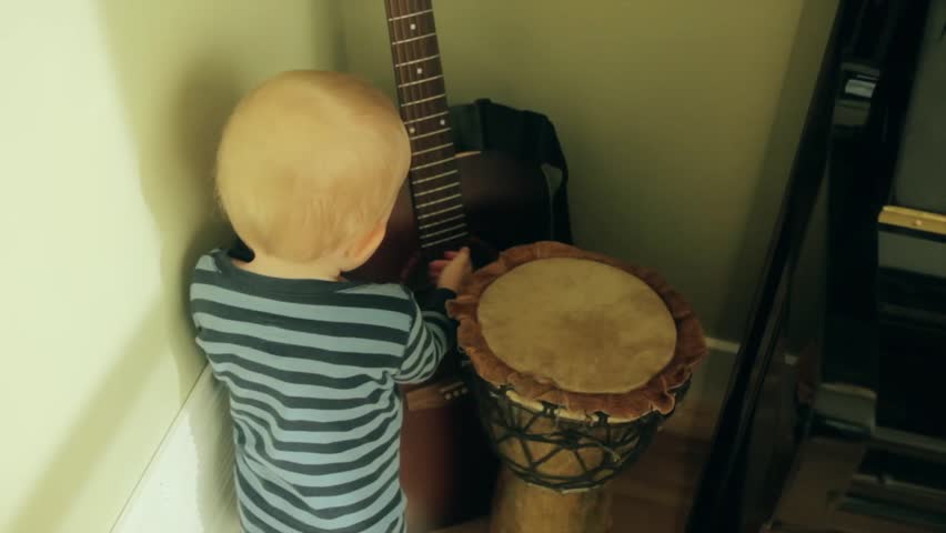 A little boy playing with a guitar and a drum
