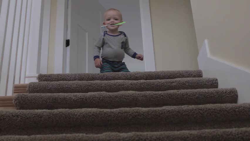 A little baby boy playing on the stairs of his house
