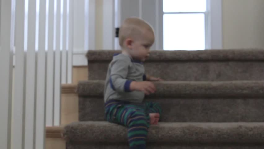 A little baby boy playing on the stairs of his house