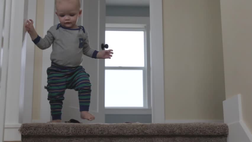 A baby boy trying to go down the stairs by himself