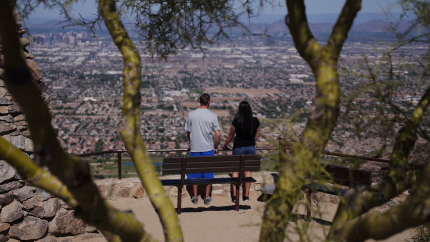 A young couple looks over Phoenix from atop of South Mountain.