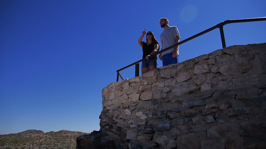 A young couple stops at an overlook in the desert.