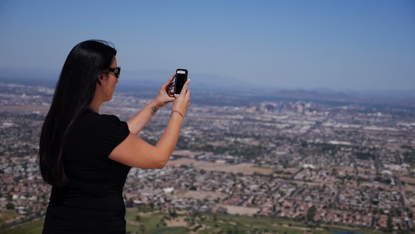 A young woman takes a panoramic photo of the Phoenix valley.