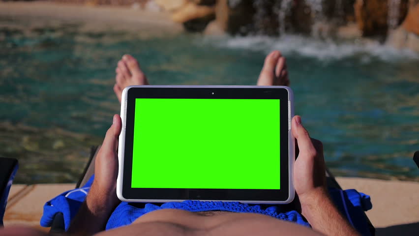A young man uses a tablet PC near the pool. User POV. Greenscreen with optional