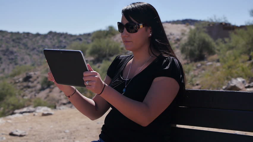 A young woman uses a tablet PC in a desert park.