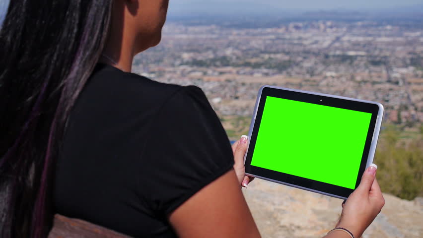 A young woman uses a tablet PC in a desert park. Greenscreen with optional
