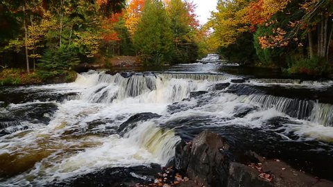Loop features whitewater cascading over rock ledges as brilliantly colorful fall leaves blow in the breeze. Shot at Bond Falls, a waterfall in Michigan's western Upper Peninsula. 30 sec. loop.