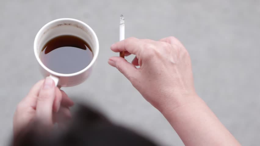 Woman smoking a cigarette and drinking coffee from her cup. Unhealthy concept