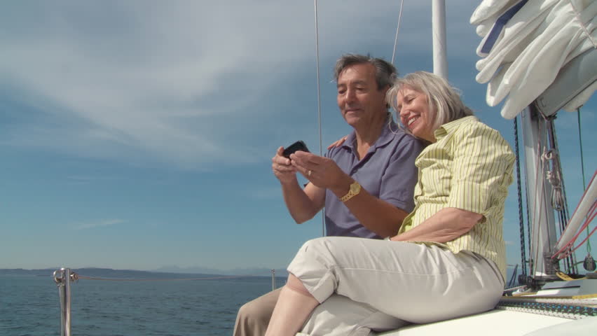 Mature couple photograph themselves with a smartphone while sailing on the Puget