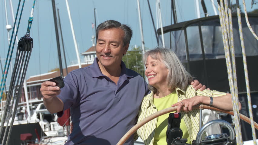 Mature couple photograph themselves with a smartphone before they set sail. Shot
