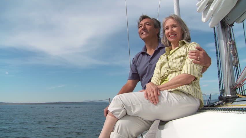 Mature couple enjoy each others' company, sitting on the deck of a boat, sailing