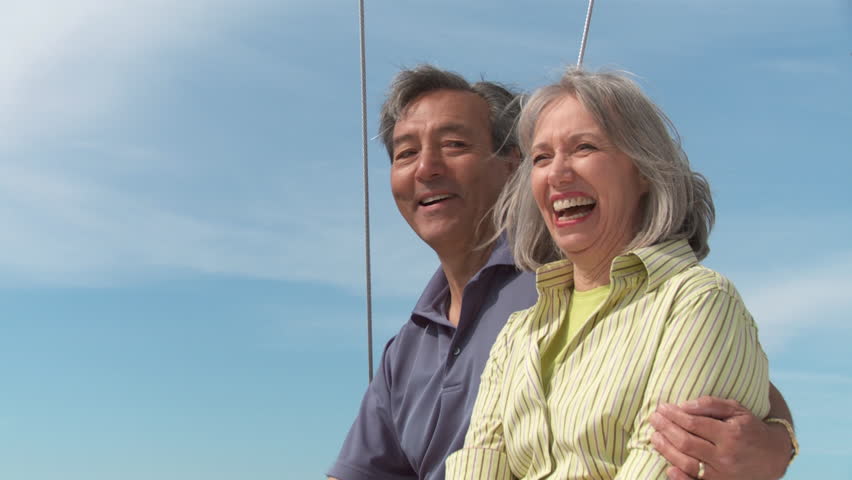 Happy mature couple sitting on a sail boat and enjoying each others' company. 