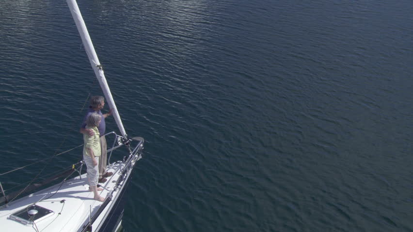 Overhead view of mature couple standing at the front of a yacht as it sails out
