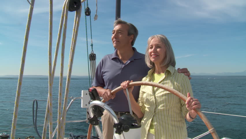 Happy mature couple taking the helm of a yacht on the Puget Sound in Seattle,