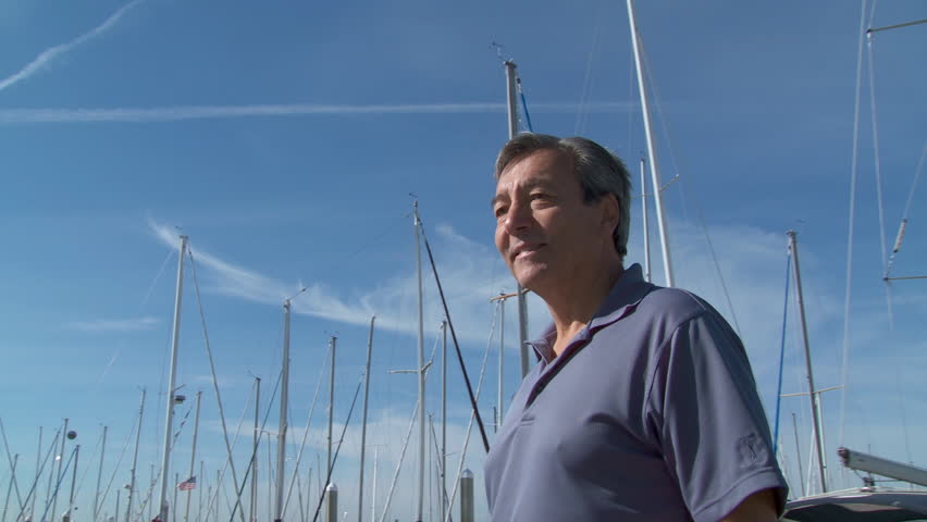 Happy mature man standing sitting on a sail boat as it passes, on the Puget